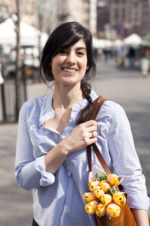Porträt einer Frau, die auf der Straße stehend ihre Handtasche hält - CAVF06062