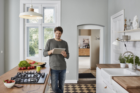 Smiling man using tablet in kitchen stock photo