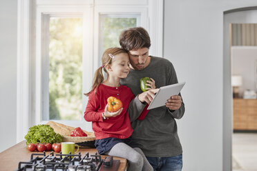 Vater und Tochter mit Paprika und Tablet in der Küche - RORF01136