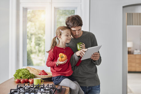 Father and daughter with bell pepper and tablet in kitchen - RORF01136