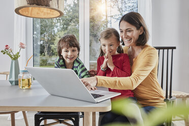Glückliche Mutter mit zwei Kindern, die zu Hause einen Laptop benutzen - RORF01160