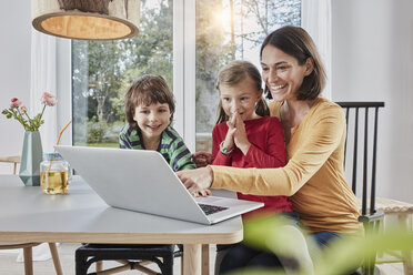 Happy mother with two children using laptop at home - RORF01160