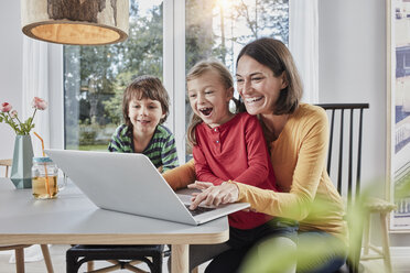 Glückliche Mutter mit zwei Kindern, die zu Hause einen Laptop benutzen - RORF01161