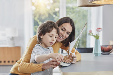 Happy mother and son playing with model boat at home - RORF01174