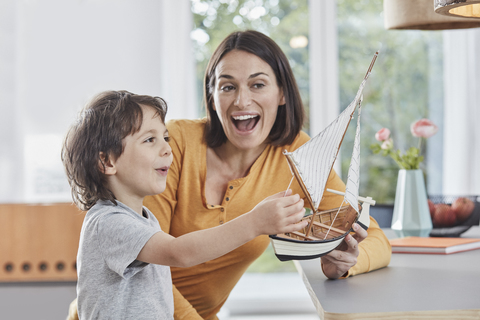 Glückliche Mutter und Sohn spielen zu Hause mit einem Modellboot, lizenzfreies Stockfoto