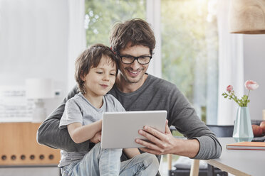 Glücklicher Vater und Sohn nutzen gemeinsam ein Tablet zu Hause - RORF01177