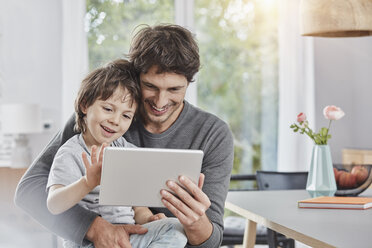 Glücklicher Vater und Sohn nutzen gemeinsam ein Tablet zu Hause - RORF01178