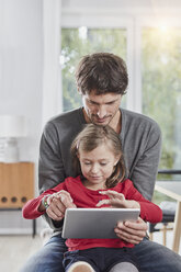 Vater und Tochter nutzen gemeinsam ein Tablet zu Hause - RORF01179