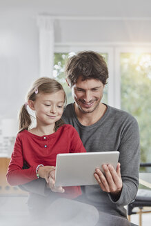 Smiling father and daughter using tablet at home together - RORF01180