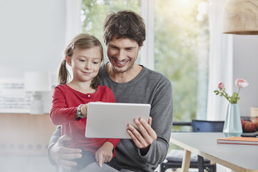 Smiling father and daughter using tablet at home together - RORF01181