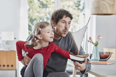 Happy father and daughter playing with model boat at home - RORF01182