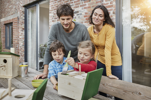 Familie arbeitet an einem Vogelhaus vor ihrem Haus, lizenzfreies Stockfoto