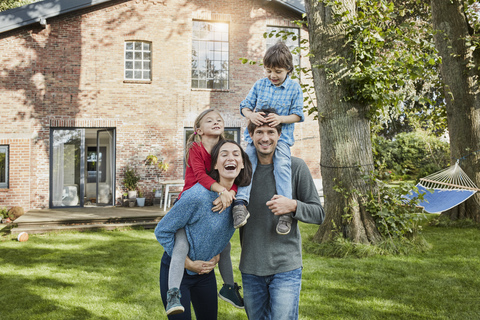 Porträt einer glücklichen Familie im Garten ihres Hauses, lizenzfreies Stockfoto