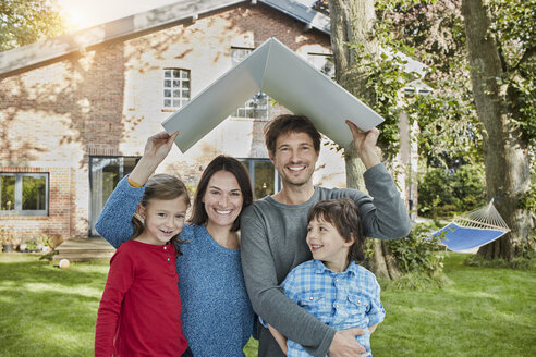 Portrait of happy family in garden of their home holding roof - RORF01229