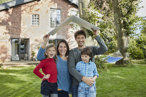 Portrait of happy family in garden of their home holding roof - RORF01230