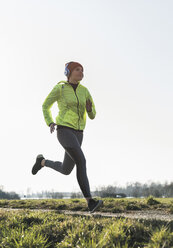 Young woman with headphones running on rural path - UUF13045