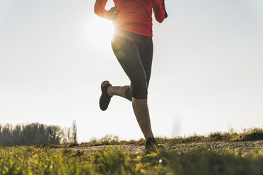 Low section of woman running on rural path - UUF13050