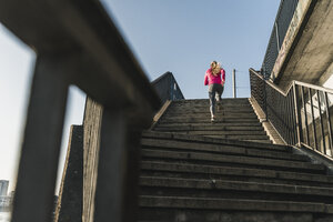 Junge Frau läuft eine Treppe hinauf - UUF13055