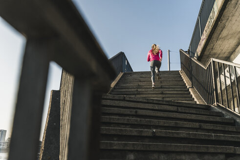 Young woman running up stairs - UUF13055