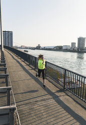 Junge Frau läuft auf Brücke am Flussufer - UUF13065