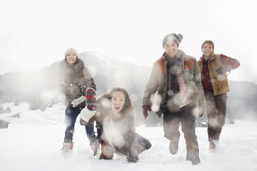 Portrait of friends playing in snowy field - CAIF12345