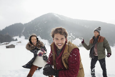 Porträt von verspielten Freunden, die auf einem Feld Schneebälle werfen - CAIF12357