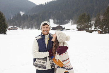Couple hugging and laughing in snowy field - CAIF12365