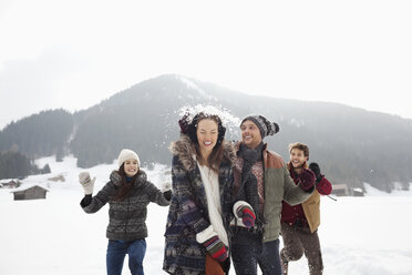 Playful friends enjoying snowball fight in field - CAIF12371