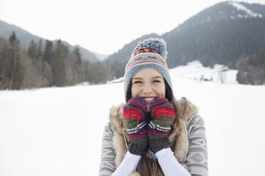 Portrait of enthusiastic woman wearing knit hat and gloves in snowy field - CAIF12373