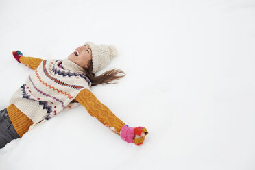 Enthusiastic woman making snow angel - CAIF12379