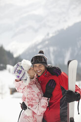 Glückliches Paar mit Skiern küsst sich im verschneiten Feld - CAIF12385
