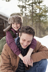 Portrait of happy son hugging father in snow - CAIF12392