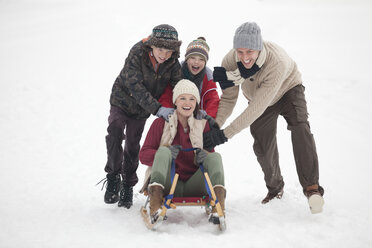 Happy family sledding in snow - CAIF12423