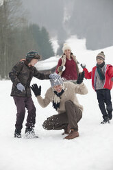 Happy family enjoying snowball fight in field - CAIF12427