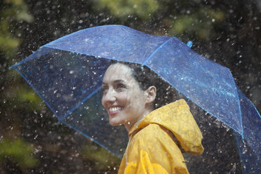 Happy woman with umbrella in rain - CAIF12434