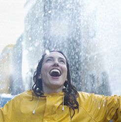 Enthusiastic woman standing in rain - CAIF12441