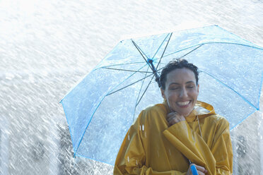 Glückliche Frau unter Regenschirm im Regen - CAIF12443