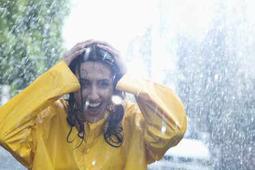 Glückliche Frau mit Händen auf dem Kopf im Regen - CAIF12444