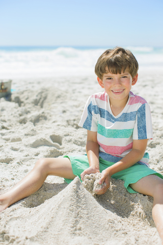 Junge baut Sandburg am Strand, lizenzfreies Stockfoto