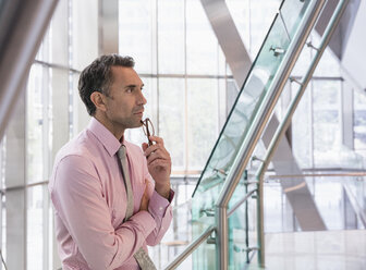 Pensive corporate businessman in modern office lobby - CAIF12465