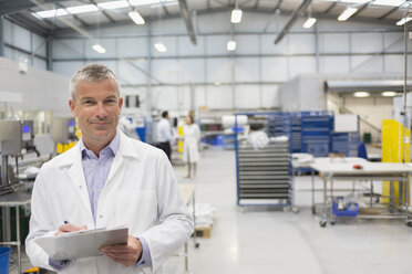 Portrait smiling engineer with clipboard in steel factory - CAIF12518