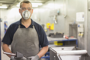 Porträt eines selbstbewussten Arbeiters mit Schutzmaske in einem Stahlwerk - CAIF12539