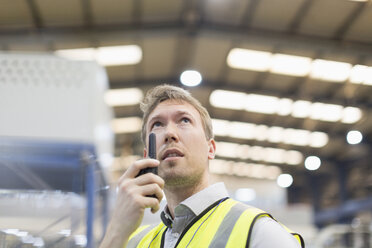 Aufsichtsperson mit Walkie-Talkie in einem Stahlwerk - CAIF12548