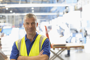 Porträt eines lächelnden Arbeiters mit Ohrstöpseln in einer Stahlfabrik - CAIF12571