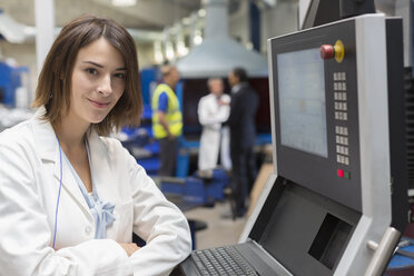 Portrait smiling female engineer at control panel in steel factory - CAIF12574