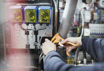 Worker using tool on machinery in steel factory - CAIF12581