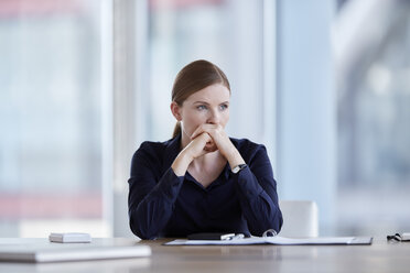 Pensive businesswoman looking away in conference room - CAIF12647