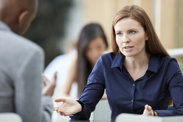 Businesswoman gesturing and talking to businessman - CAIF12658