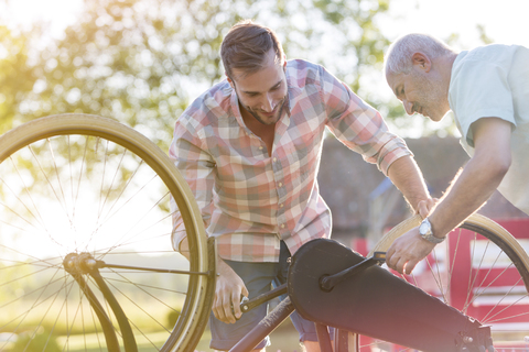 Vater und erwachsener Sohn reparieren Fahrrad, lizenzfreies Stockfoto