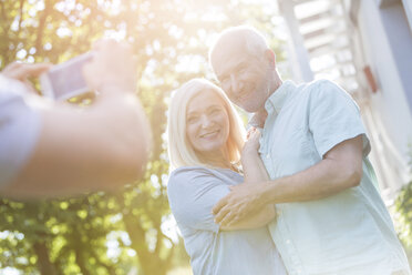 Man photographing senior couple outdoors - CAIF12683